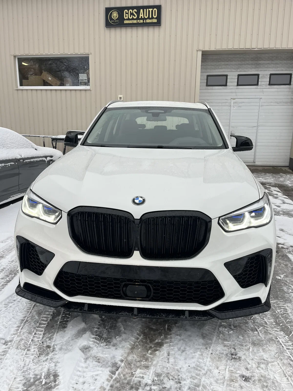 Valge BMW iX eestvaade GCS Auto töökoja ees